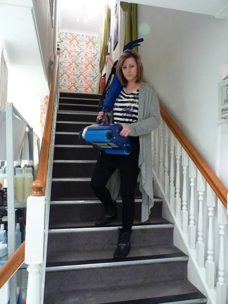 Woman effortlessly carrying the Duplex 280 Floor Cleaner down stairs, showcasing its exceptional portability and ease of use