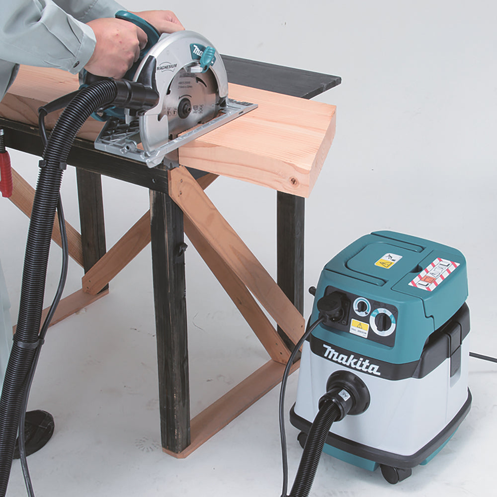 Man using a circular saw on a workbench with a Makita VC1310L/1 L Power Tool Extractor nearby for efficient dust and debris extraction during woodworking