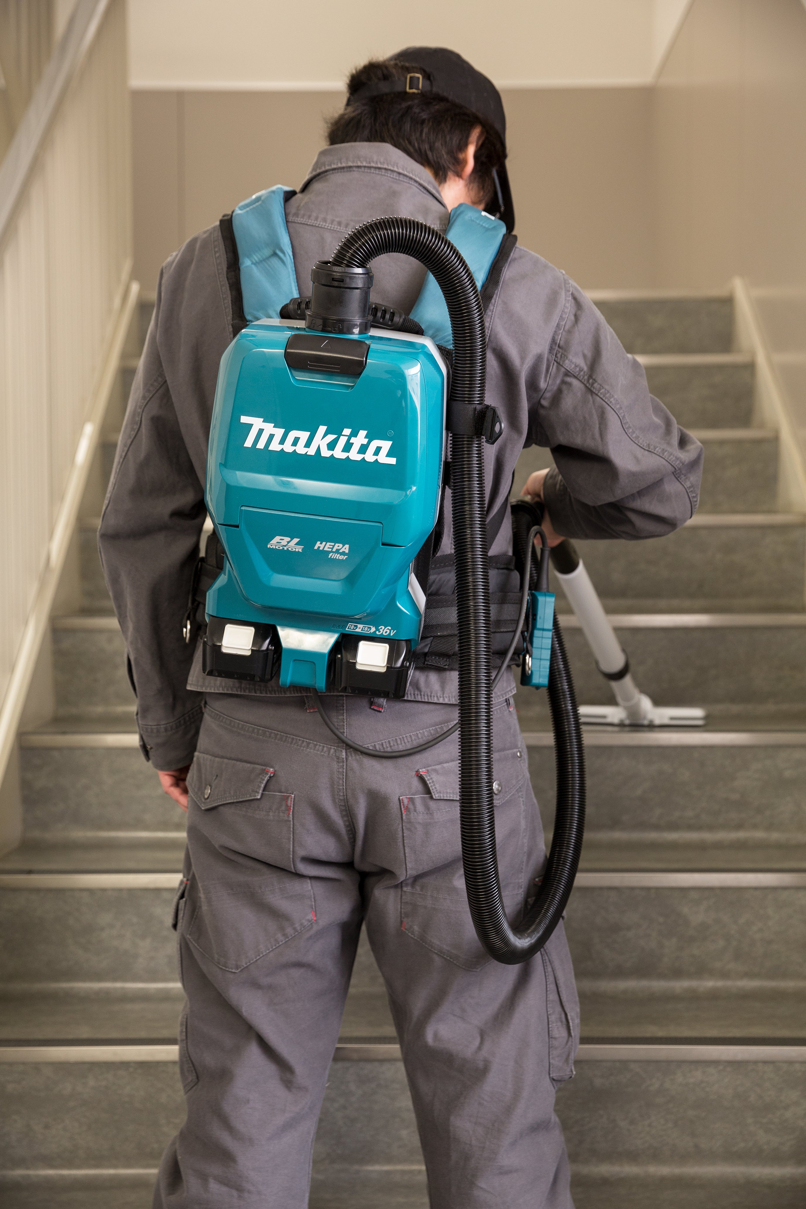 Operator using Makita DVC261TX25 cordless backpack vacuum cleaner for commercial cleaning