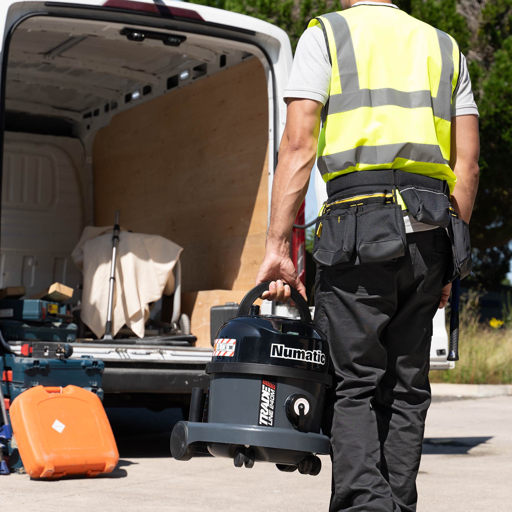 Tradesperson loading Numatic TRM240 M-Class vacuum cleaner into a work van for mobile dust extraction