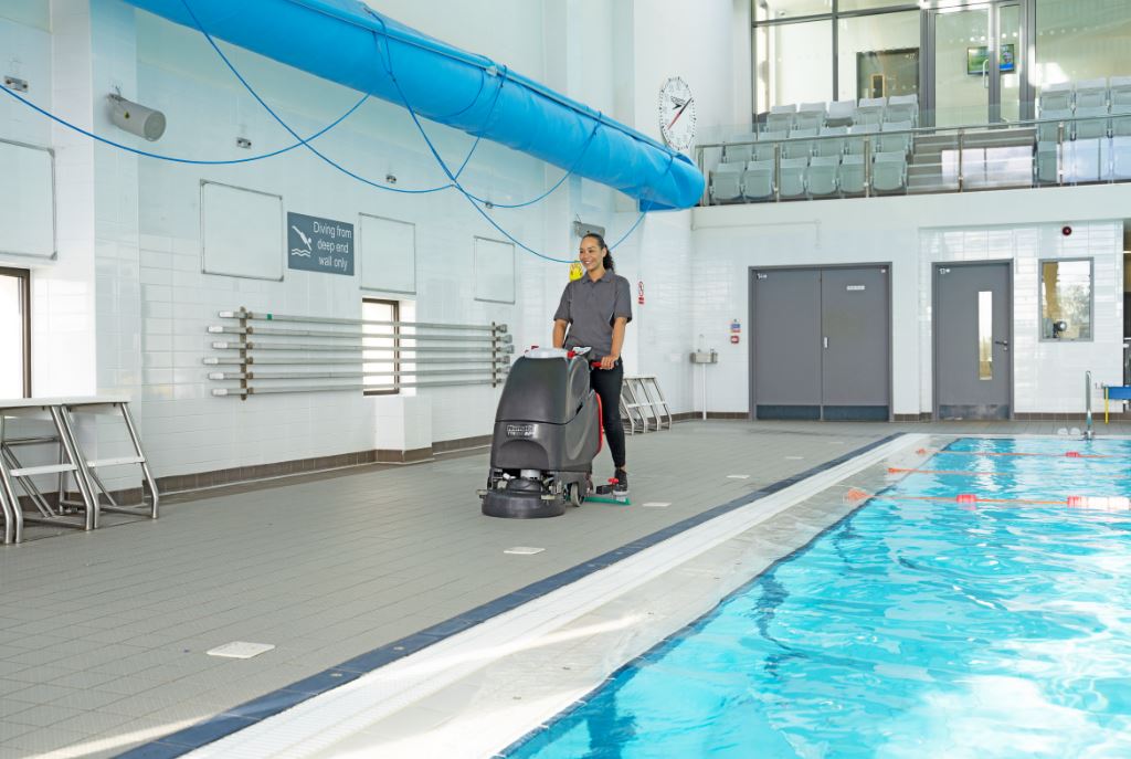 Numatic TTB3045NX being used for commercial hard floor cleaning beside a swimming pool