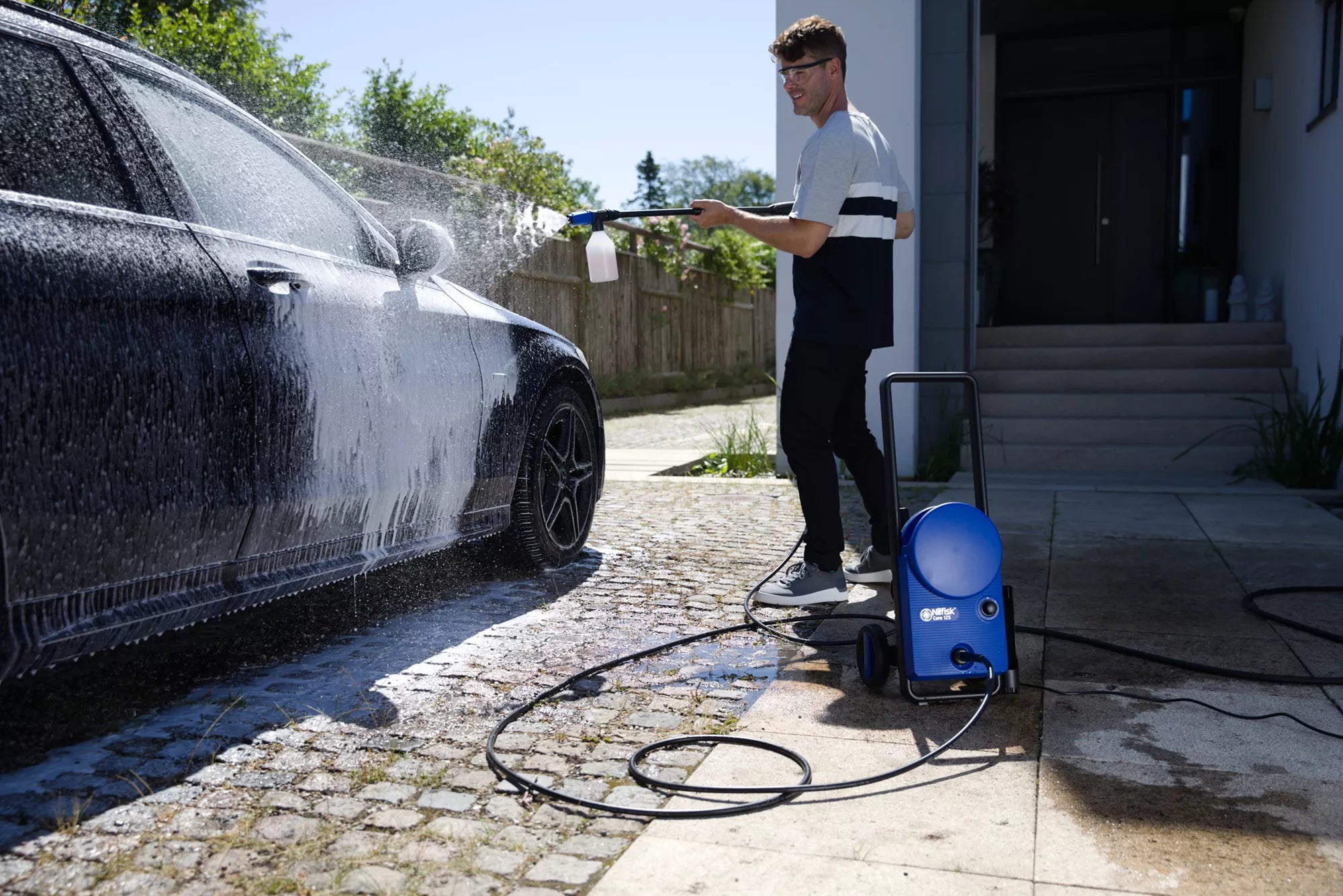 Man using an industrial pressure washer to clean the back of a lorry at the depot