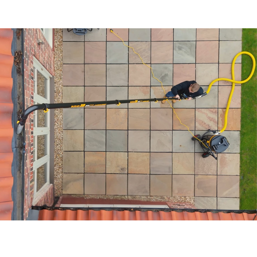 Operator using V-TUF GCX8000 gutter vacuum cleaner from ground level to remove debris from building gutters