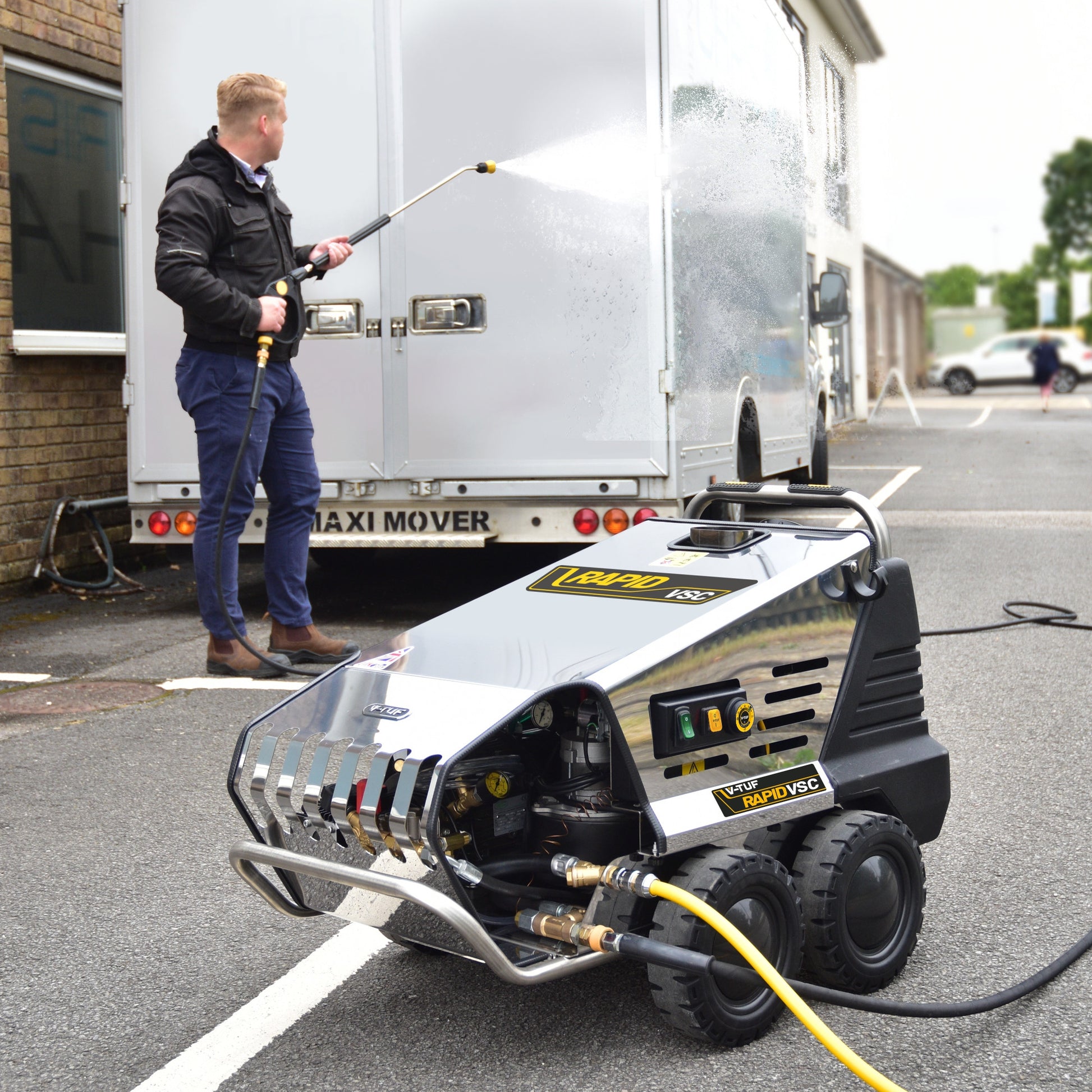 Operator manoeuvring the V-TUF Rapid VSC hot pressure washer using heavy-duty wheels and ergonomic handles