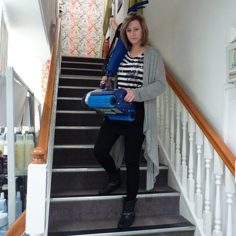 Woman effortlessly carrying the Duplex 280 Floor Cleaner down stairs, showcasing its exceptional portability and ease of use
