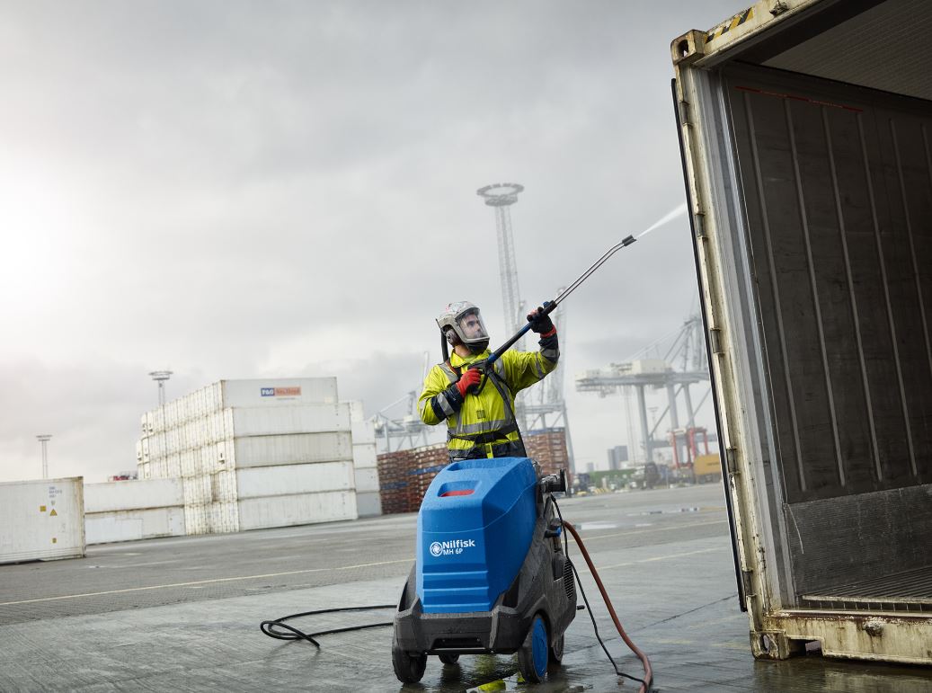 Man using an industrial pressure washer to clean the back of a lorry at the depot