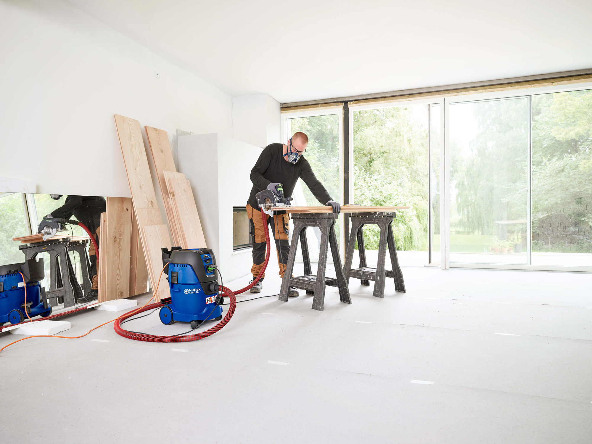Operator using Nilfisk Aero 26-2H H-Class vacuum in workshop to extract fine dust and debris