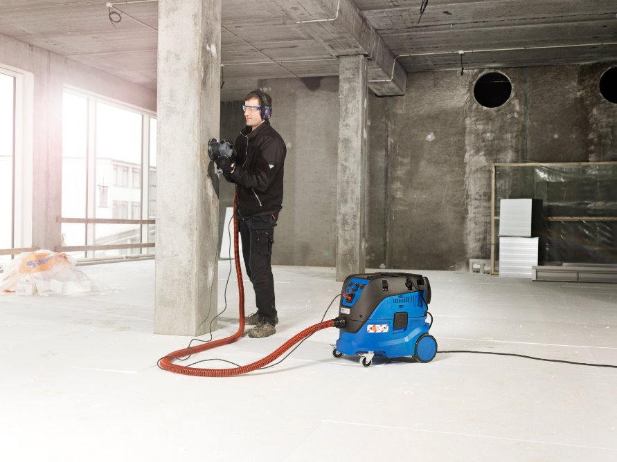 Operator using Nilfisk Attix 33-2M PC M-Class hoover for dust extraction on a construction or renovation site