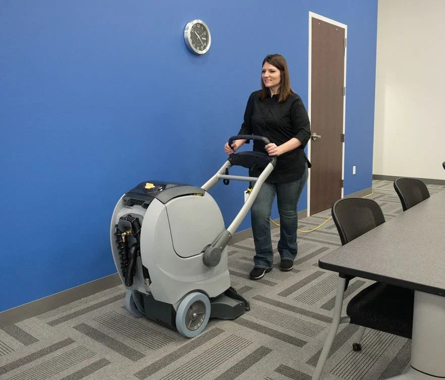 Operator using Nilfisk ES300 industrial carpet cleaning machine on large carpeted area