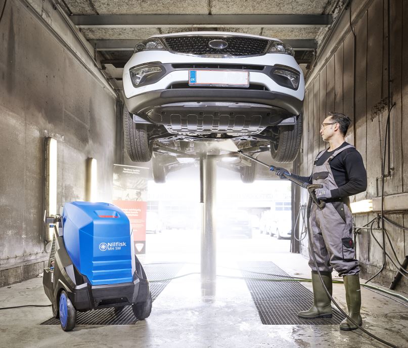 Nilfisk MH5M hot jet washer being used in an industrial wash bay for heavy-duty cleaning tasks