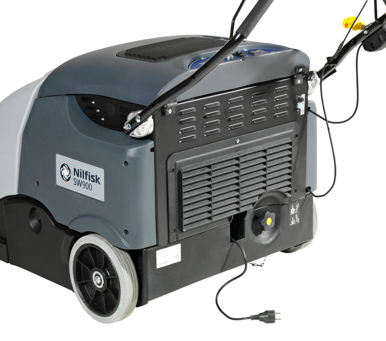Operator charging Nilfisk SW900 industrial floor sweeper at docking station